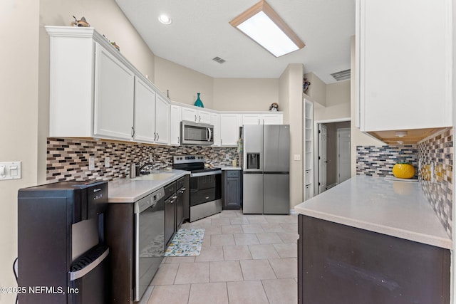 kitchen with backsplash, white cabinetry, appliances with stainless steel finishes, and a sink