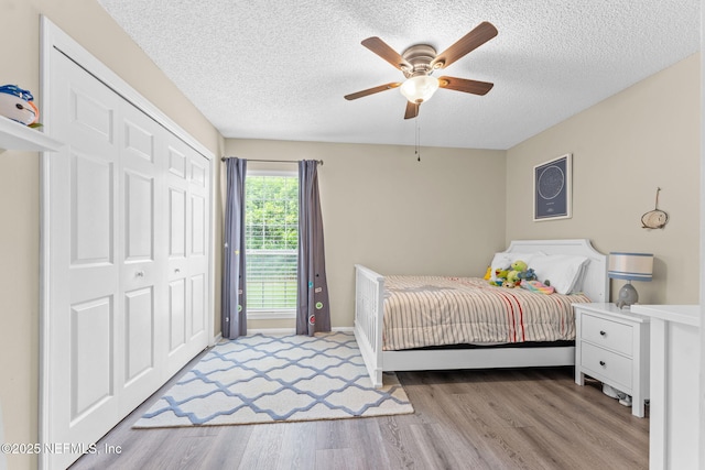 bedroom featuring a textured ceiling, ceiling fan, a closet, and light wood-style flooring