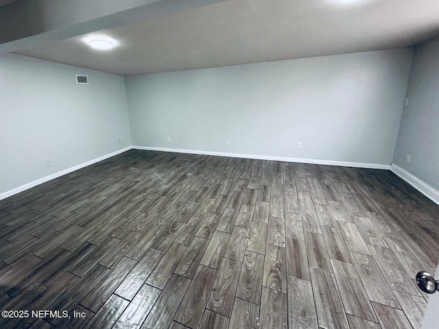 unfurnished room featuring baseboards, dark wood-style flooring, and visible vents