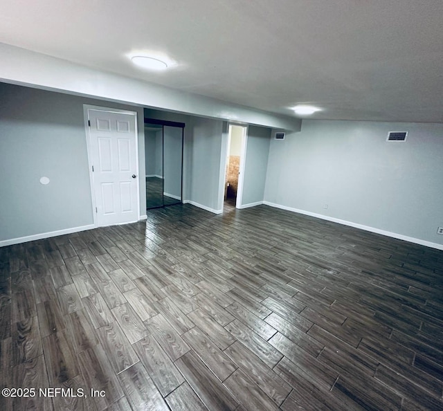 finished basement with dark wood-style flooring, baseboards, and visible vents