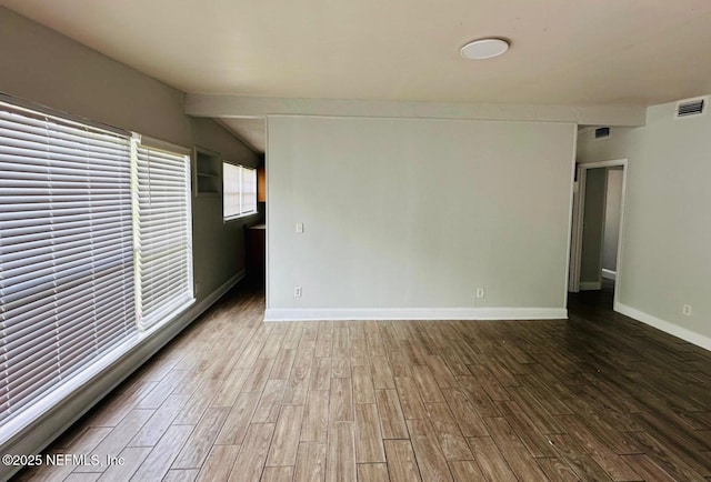 unfurnished room featuring baseboards, vaulted ceiling with beams, wood finished floors, and visible vents