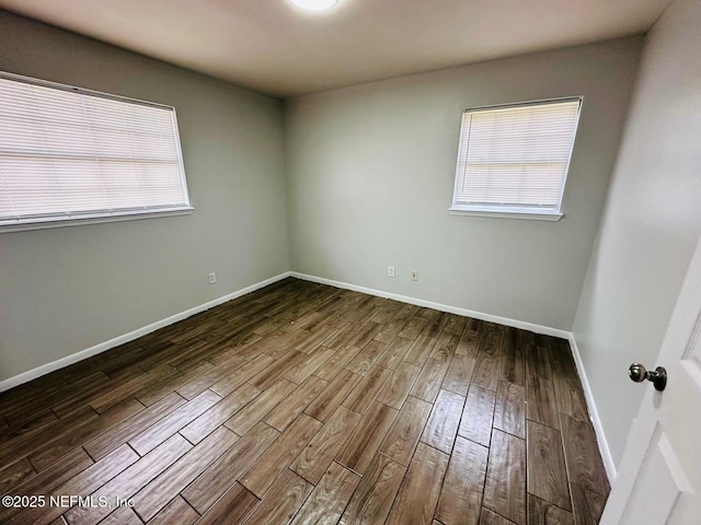 unfurnished room featuring baseboards and dark wood-style floors