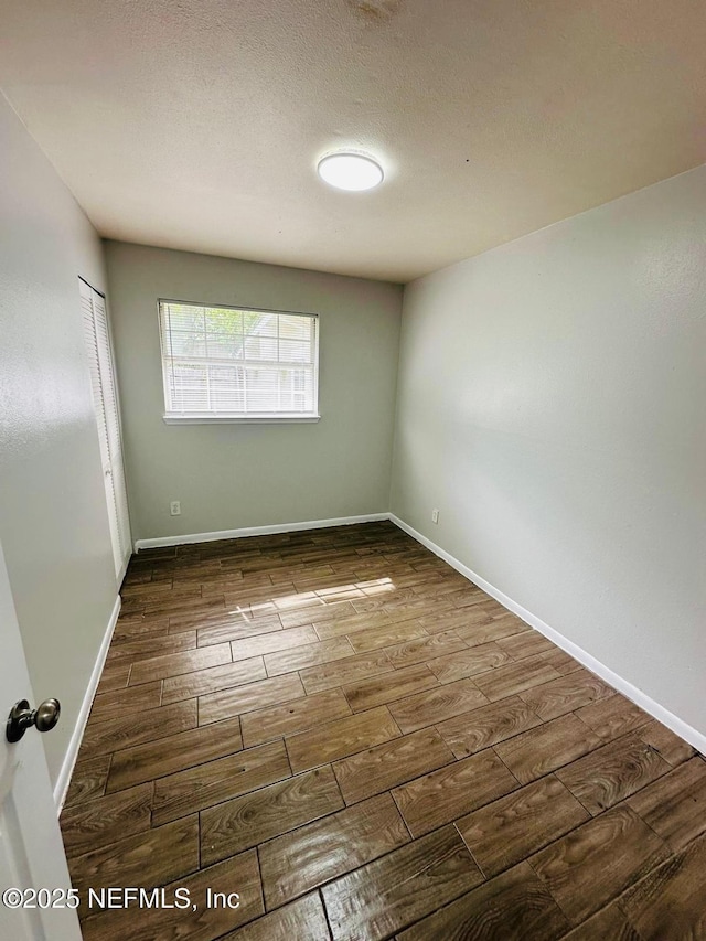unfurnished room with baseboards and wood finished floors