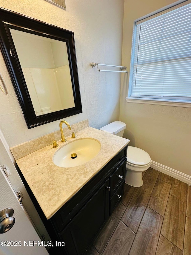 bathroom with vanity, baseboards, wood finished floors, and toilet