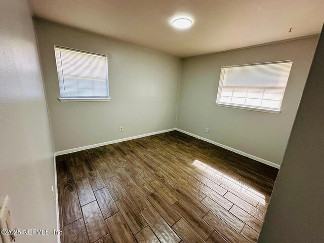 spare room featuring baseboards and wood finished floors