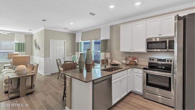119 Craig Ct, Saint Johns, FL 32092 - kitchen featuring crown molding, a peninsula, a sink, light wood-style flooring, and appliances with stainless steel finishes