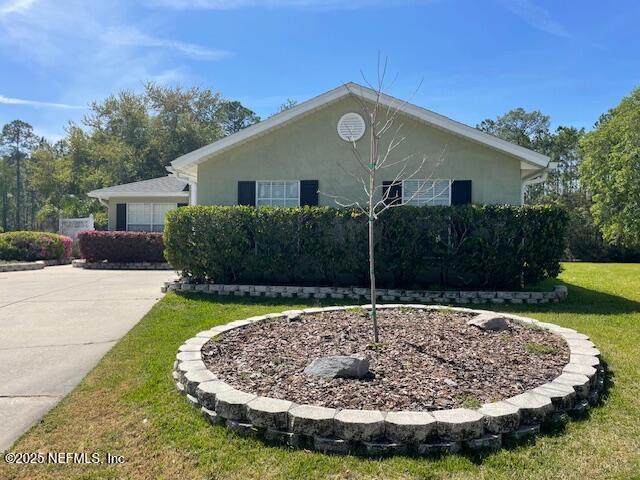 1831 Moss Creek Dr SW, Fleming Island, FL 32003 - view of side of property featuring stucco siding, a yard, and concrete driveway