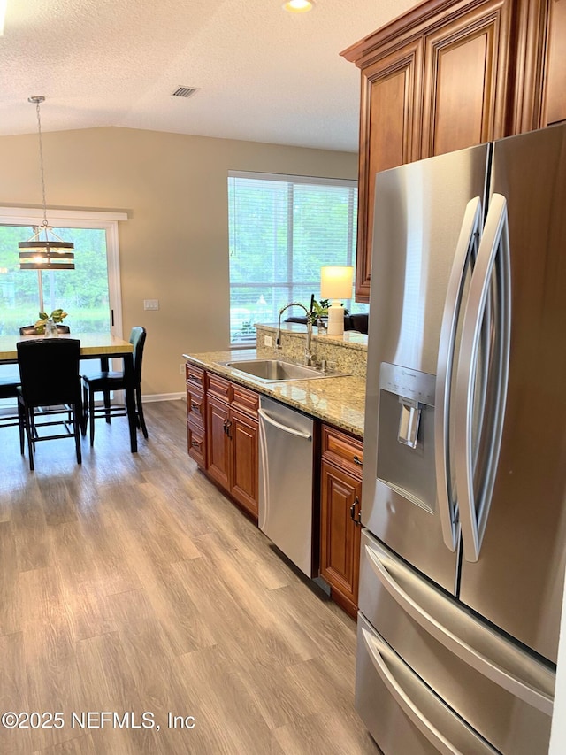 1831 Moss Creek Dr SW, Fleming Island, FL 32003 - kitchen with brown cabinetry, visible vents, light wood-style floors, a sink, and appliances with stainless steel finishes