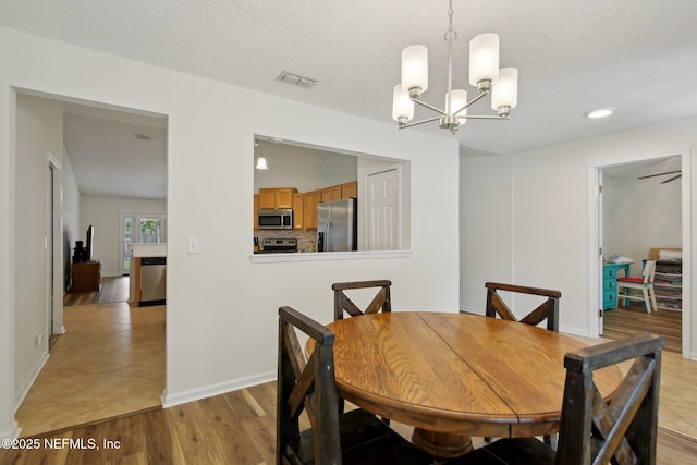 13198 Ebbtide Ct, Jacksonville, FL 32225 - dining space featuring a chandelier, light wood-style floors, a textured ceiling, and baseboards