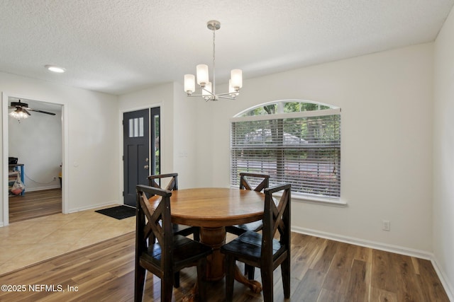 13198 Ebbtide Ct, Jacksonville, FL 32225 - dining room featuring a chandelier, light wood finished floors, a textured ceiling, baseboards, and a ceiling fan