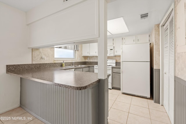 8195 Trafalgar Sq, Jacksonville, FL 32217 - kitchen featuring white appliances, visible vents, a sink, a peninsula, and dark countertops