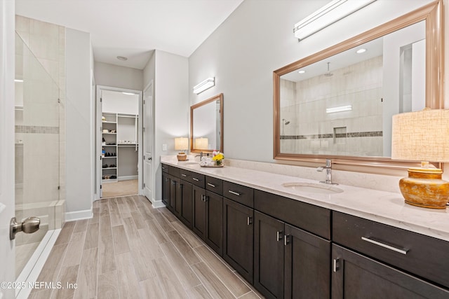 full bath featuring double vanity, tiled shower, and a sink