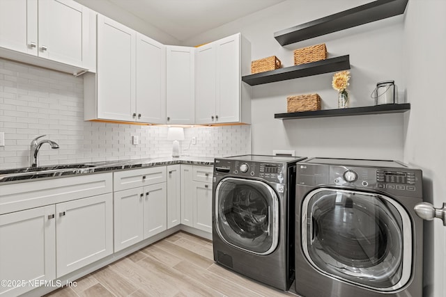 clothes washing area featuring a sink, light wood-style flooring, cabinet space, and independent washer and dryer