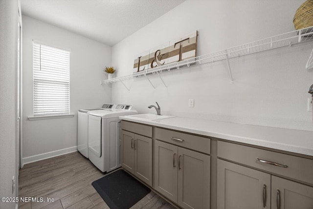 77 Palisade Dr, Saint Augustine, FL 32092 - laundry area featuring light wood-type flooring, cabinet space, a sink, baseboards, and washer and clothes dryer