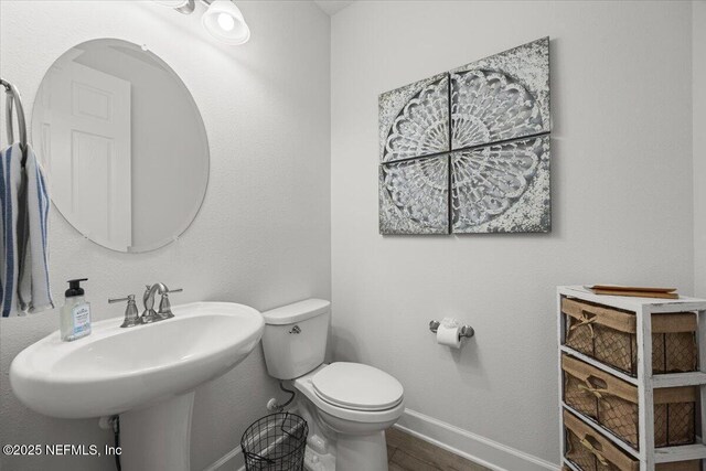 77 Palisade Dr, Saint Augustine, FL 32092 - half bath featuring toilet, baseboards, a sink, and wood finished floors
