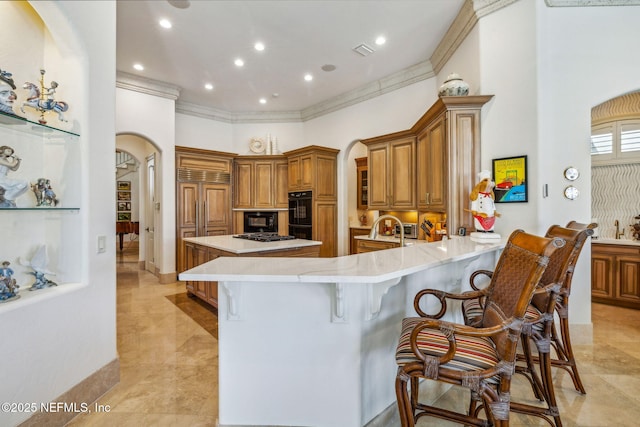 108 Harbourmaster Ct, Ponte Vedra Beach, FL 32082 - kitchen with arched walkways, brown cabinetry, light countertops, a kitchen bar, and crown molding
