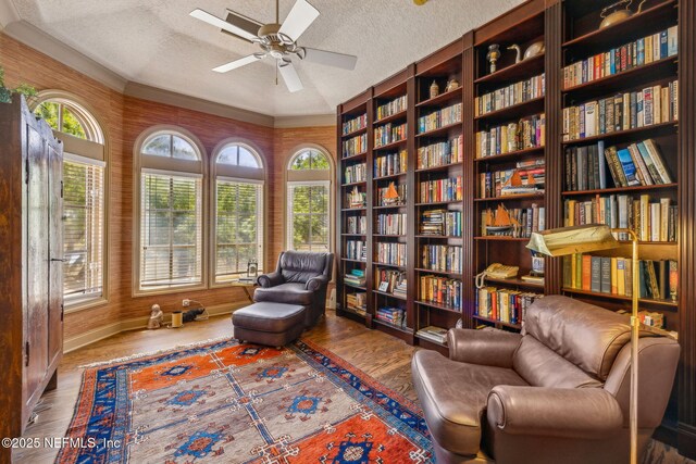 108 Harbourmaster Ct, Ponte Vedra Beach, FL 32082 - sitting room with wall of books, a textured ceiling, wood finished floors, ceiling fan, and baseboards