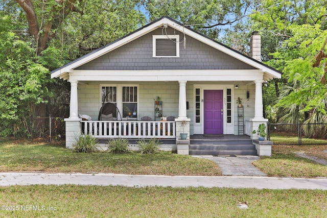 bungalow with a porch, a front lawn, fence, and a chimney