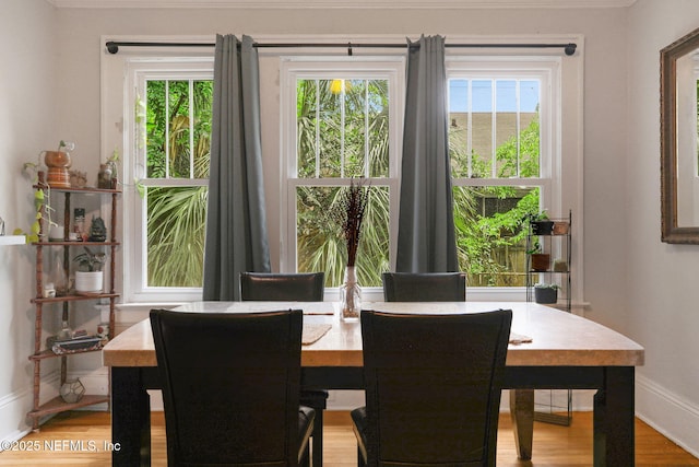 dining room with baseboards, ornamental molding, and light wood-style floors