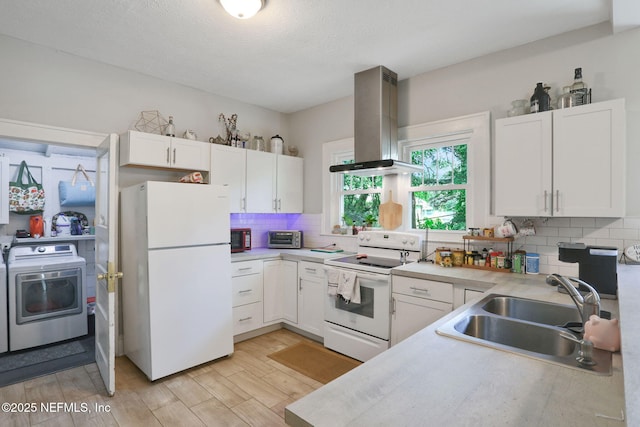 kitchen with white appliances, washer / clothes dryer, wall chimney exhaust hood, white cabinets, and a sink
