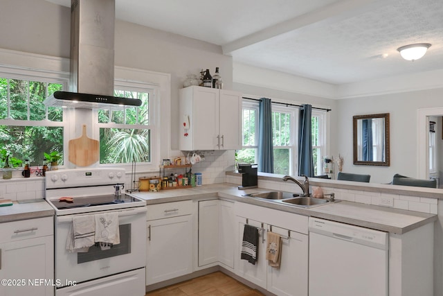 kitchen featuring a sink, backsplash, island range hood, and white appliances