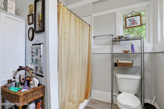 bathroom with toilet, baseboards, and a shower with curtain