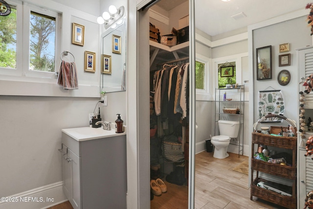 bathroom with vanity, a spacious closet, and toilet