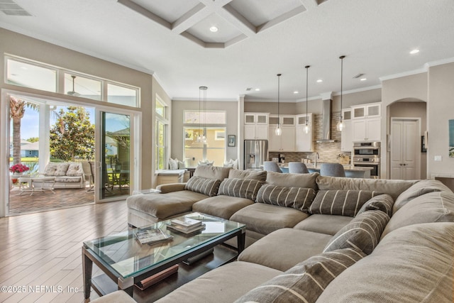 living room featuring visible vents, crown molding, arched walkways, hardwood / wood-style flooring, and recessed lighting