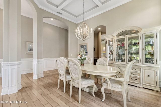 dining area with arched walkways, beam ceiling, light wood finished floors, a chandelier, and coffered ceiling