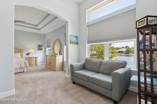 carpeted bedroom with arched walkways, baseboards, and a water view