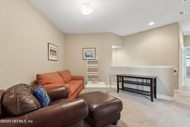 carpeted living area with baseboards, a textured ceiling, and visible vents