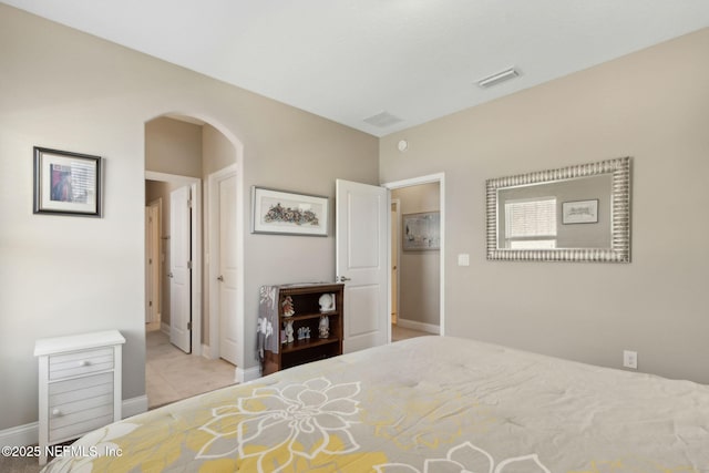 tiled bedroom featuring arched walkways, baseboards, and visible vents