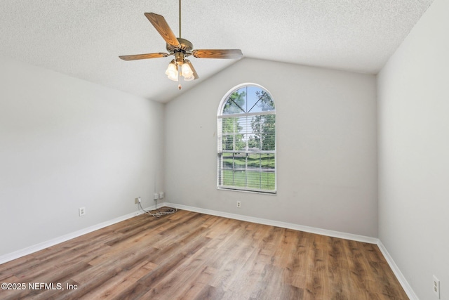 6085 Bermuda Dr, Fleming Island, FL 32003 - spare room with a textured ceiling, wood finished floors, vaulted ceiling, a ceiling fan, and baseboards