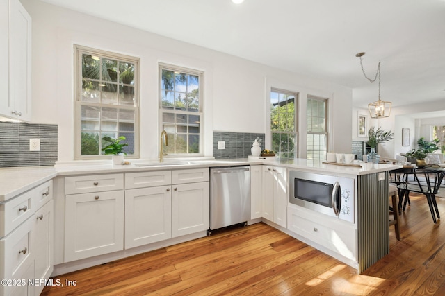 2930 Apache Ave, Jacksonville, FL 32210 - kitchen with stainless steel appliances, a sink, decorative backsplash, a peninsula, and white cabinets
