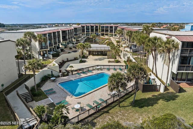 community pool with a fenced backyard and a patio area