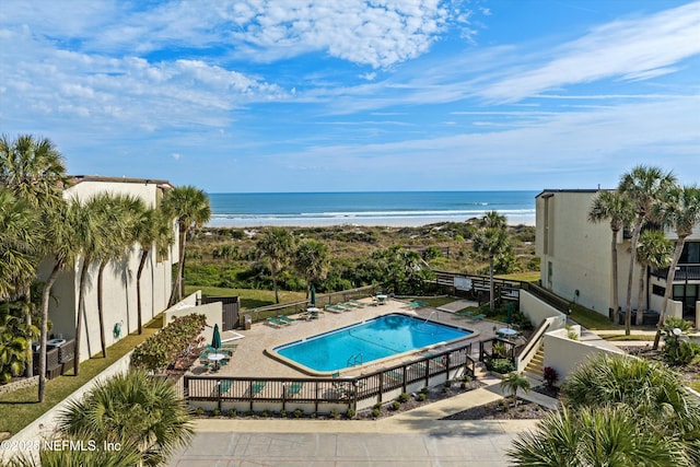 community pool featuring fence, a patio, and a water view