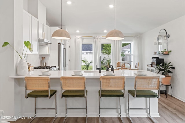 80 Boulder Ln, Saint Johns, FL 32259 - kitchen featuring high quality fridge, under cabinet range hood, light countertops, a kitchen breakfast bar, and decorative light fixtures