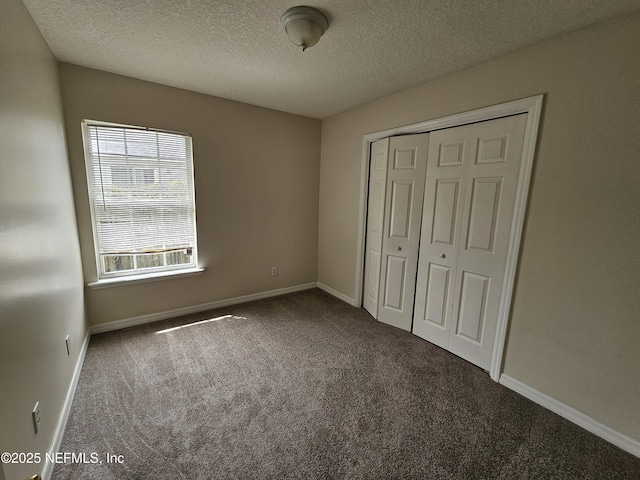 unfurnished bedroom with a closet, carpet flooring, a textured ceiling, and baseboards