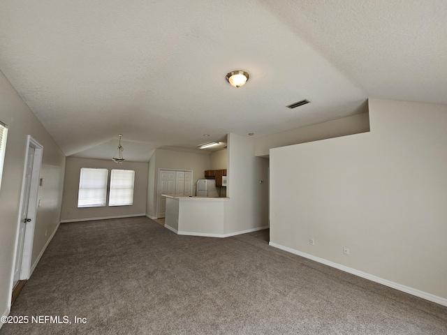 unfurnished living room with a textured ceiling, vaulted ceiling, visible vents, and dark colored carpet