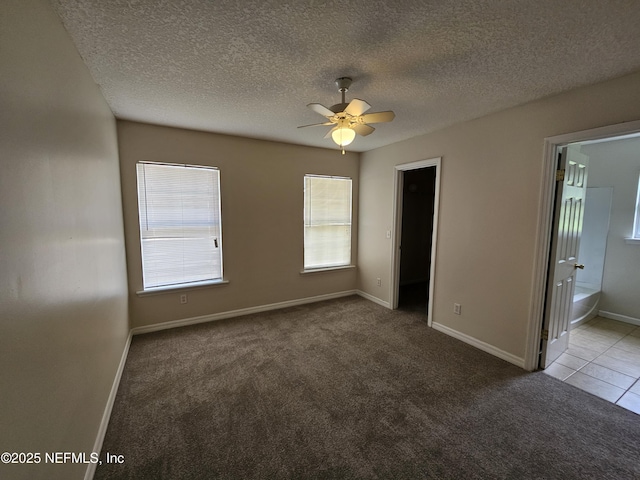 unfurnished bedroom featuring carpet floors, a textured ceiling, baseboards, and ensuite bath