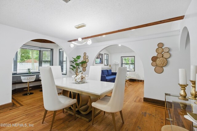 6878 Lenox Ave, Jacksonville, FL 32205 - dining area featuring baseboards, arched walkways, a textured ceiling, and wood finished floors