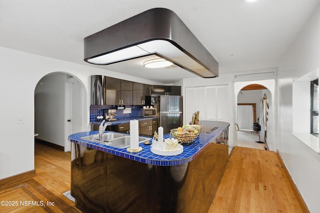 6878 Lenox Ave, Jacksonville, FL 32205 - kitchen featuring arched walkways, a sink, baseboards, tile counters, and stainless steel appliances