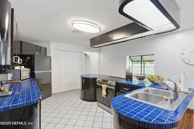 6878 Lenox Ave, Jacksonville, FL 32205 - kitchen with a textured ceiling, visible vents, appliances with stainless steel finishes, a sink, and tile counters