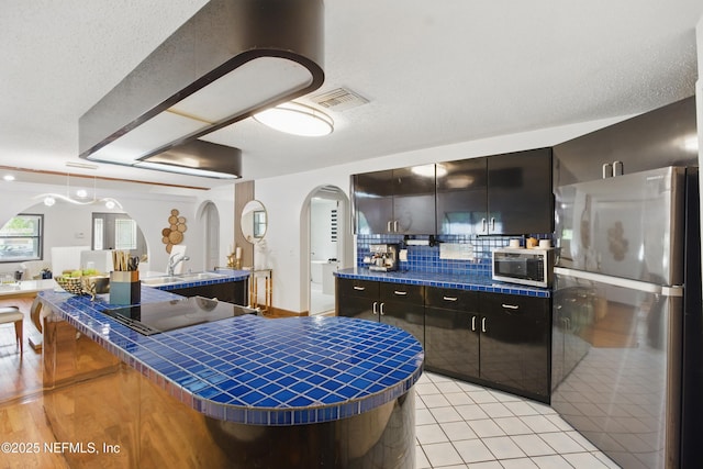 6878 Lenox Ave, Jacksonville, FL 32205 - kitchen featuring visible vents, tile countertops, arched walkways, appliances with stainless steel finishes, and backsplash