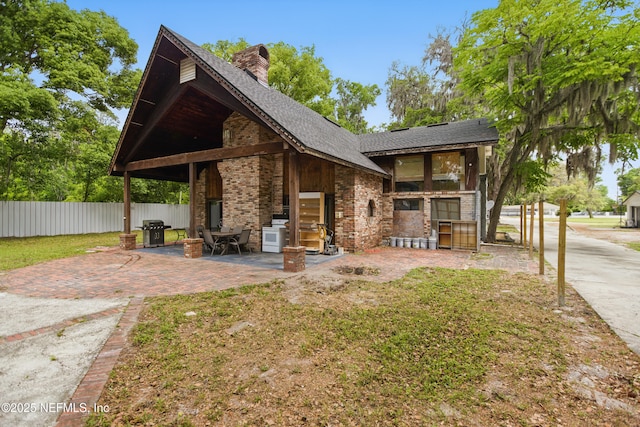 6878 Lenox Ave, Jacksonville, FL 32205 - back of house featuring a chimney, brick siding, fence, a patio, and a shingled roof