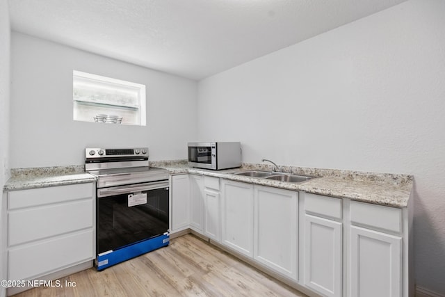 6878 Lenox Ave, Jacksonville, FL 32205 - kitchen with appliances with stainless steel finishes, a sink, light wood-style floors, light countertops, and white cabinetry
