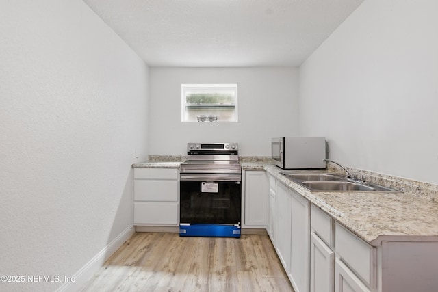 6878 Lenox Ave, Jacksonville, FL 32205 - kitchen featuring appliances with stainless steel finishes, a sink, baseboards, light countertops, and light wood-style flooring