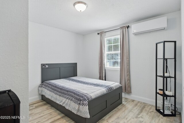 6878 Lenox Ave, Jacksonville, FL 32205 - bedroom featuring baseboards, a textured wall, wood finished floors, and a wall mounted air conditioner