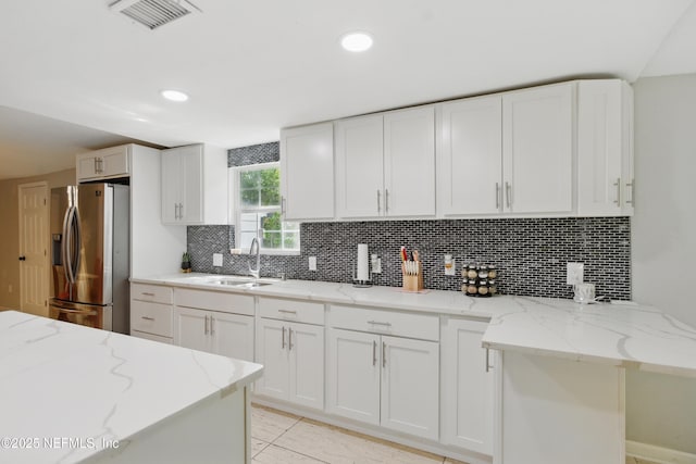 6878 Lenox Ave, Jacksonville, FL 32205 - kitchen with visible vents, stainless steel refrigerator with ice dispenser, white cabinets, tasteful backsplash, and a sink