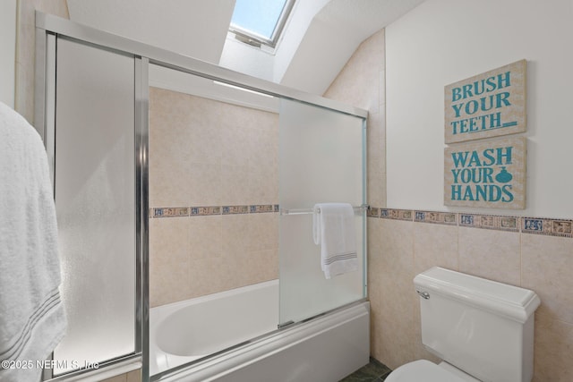 2762 Seagate Ave, Jacksonville Beach, FL 32250 - bathroom featuring toilet, a skylight, tile walls, and bath / shower combo with glass door